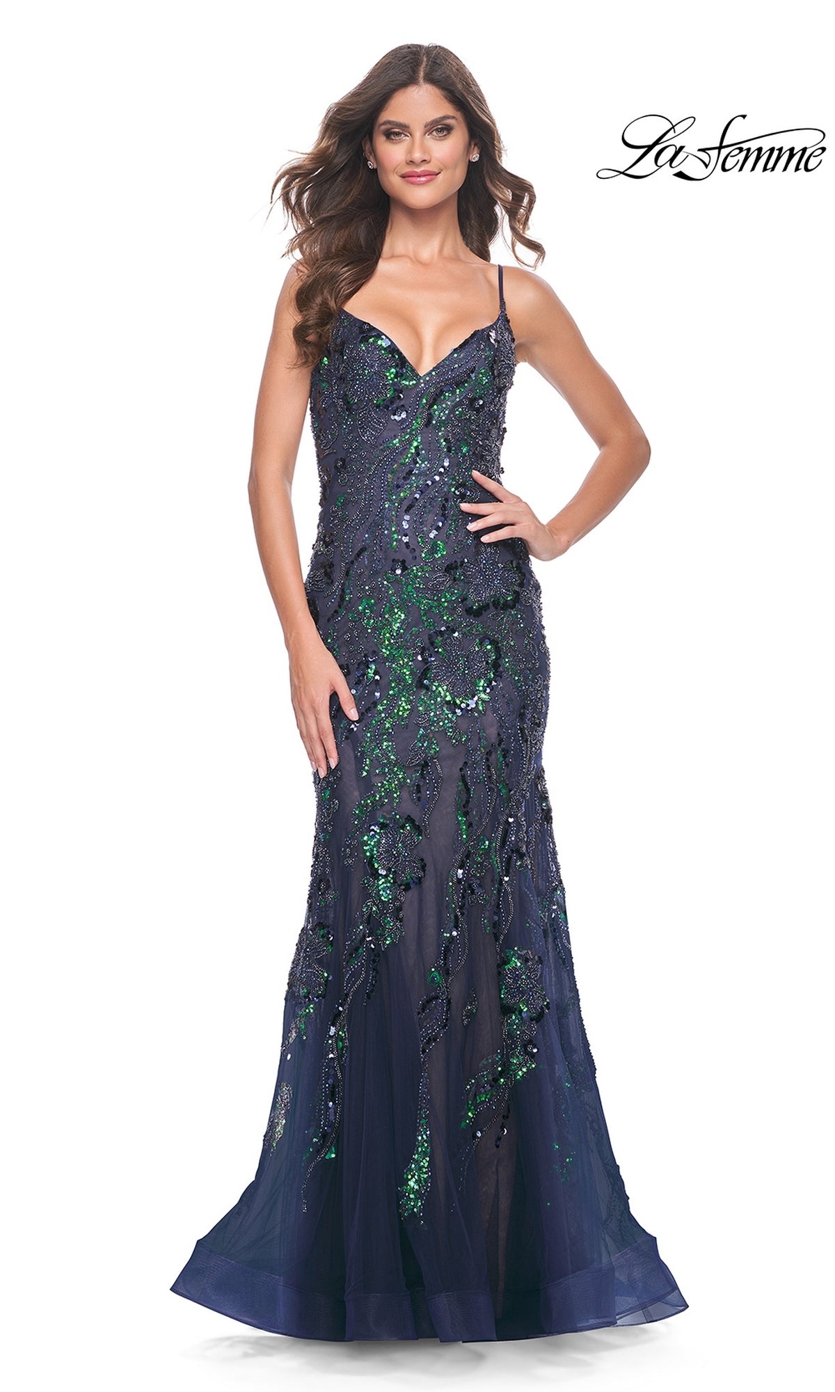 A woman models the Le Femme Sequin-Lace Long Mermaid Prom Dress 32049, featuring a navy blue floor-length design with green sequin embellishments and thin straps, against a white background.